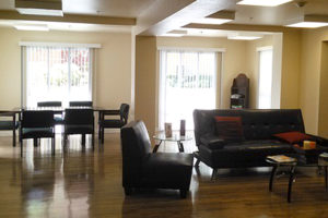 sitting area with couch and chairs, table area with chairs, large windows with light