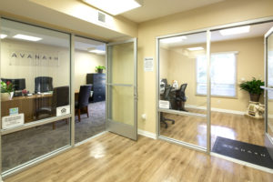 Hallway leading to business center room and office room with desk, Avanath logo, and computer