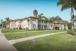 exterior of building surrounded by grass and palm trees on sunny day
