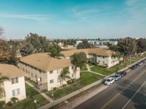 exterior of building surrounded by grass and palm trees on sunny day, aerial view