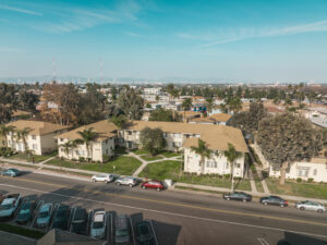 exterior of building surrounded by grass and palm trees on sunny day, aerial view