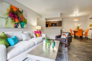 Brightly lit living room with couch, lounge chair, wood toned vinyl floor, and coffee table