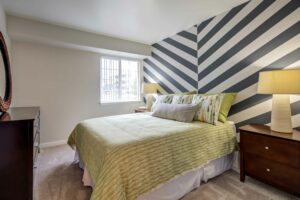 Bedroom with queen size mattress, 2 nightstands, neutral toned carpeting