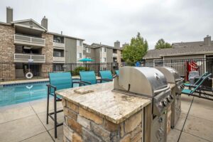 Outdoor stone cooking island adjacent to pool with seating and multiple built in grills