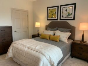 bedroom, queen-sized bed neutral toned carpeting, dresser, door left side of bed.