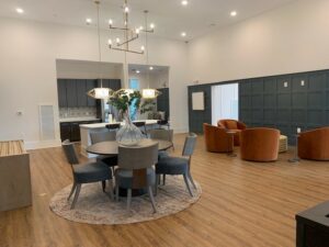 community clubhouse, kitchen island, dining table, lounge seating area, wood floors, contemporary chandelier