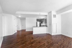Unit Kitchen/Living room, breakfast bar, open floorplan, stainless steel appliances, view from living room to kitchen to front door, hardwood floors.