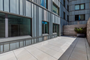 Unit patio, three windows looking into apartment unit, wooden fencing, concrete floor, spacious.