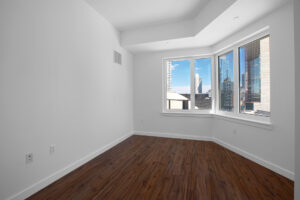 Unit Bedroom, hardwood floors, white walls, angled corner, sprawling angled corner window