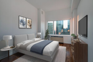 Unit Bedroom, furnished, queen size bed with nightstands on both sides, dresser with tv mounted above parallel to bed, contemporary art hung above bed, potted plant in corner near AC/furnace and window.