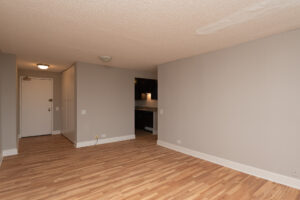 Unit Living room, entranceway on the left, wood floors, linen closet to the left when entering, kitchen in hallway leading to bedroom and bathroom.