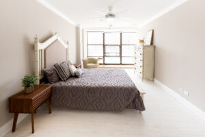 Unit bedroom, wood floors, queen size bed, dark brown night stands, floor to ceiling windows.