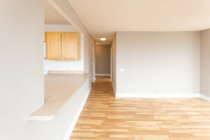 Unit Living room hallway, Wood Floors, Unfurnished, Light brown Cabinets in kitchen.