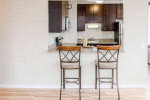Kitchen Breakfast Bar, Wood Floors, Bar stools, Granite Countertops, Dark Brown Cabinetry.