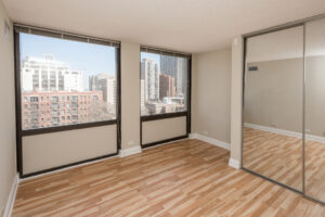 Unfurnished Unit bedroom, wood floors, 2 large windows, mirrored sliding closet doors.