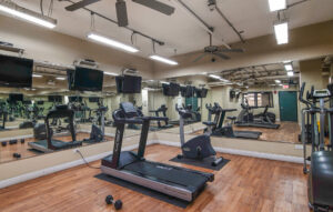 Interior Lincoln Park Plaza's Fitness Center, Wood Floors, Mirrored walls, Multiple Mounted TVs, Treadmills, Stationary bikes, Ellipticals, Free-Weights.