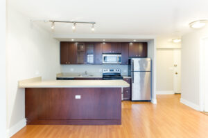 Unit Kitchen, open floorplan, kitchen attached to living room, kitchen island, stainless steel appliances, dark brown cabinetry, wood floors.