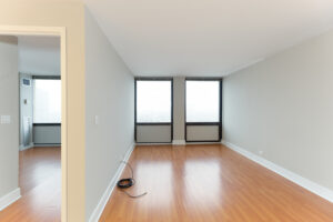 Unit Living Room, bedroom on other side of wall, wood floors, 2 large windows on farside wall.