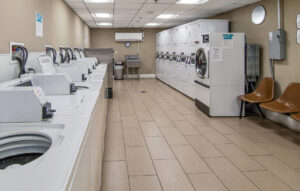 Interior Laundry Facilities, Industrial washer and dryer machines, Tile Flooring, Waiting Bench, Stainless steel Industrial sink.