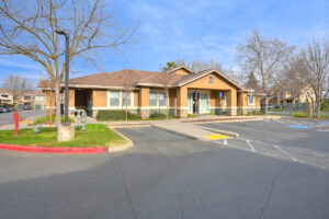 exterior leasing office, parking in front, meticulous landscaping, photo taken in winter on a sunny day.
