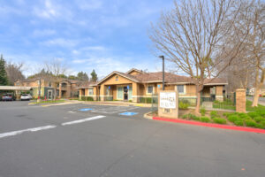 exterior leasing office, parking in front, meticulous landscaping, photo taken in winter on a sunny day.