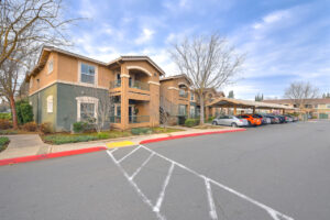 Exterior Residential building, meticulous landscaping, green and beige building, covered parking in front, trees in winter.